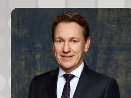 A professional headshot of Marco Ortlam, General Manager of Montage Los Cabos, smiling in a dark suit and patterned tie against a textured blue-grey.