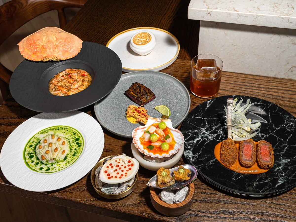 A variety of haute cuisine dishes are artfully arranged on a wooden table, showcasing refined techniques and upscale presentation.