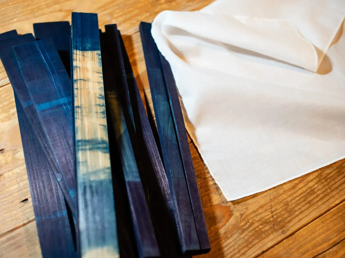 Indigo-dyed wood and white fabric on a wooden surface, showing materials used in Awa Indigo dyeing Tokushima.