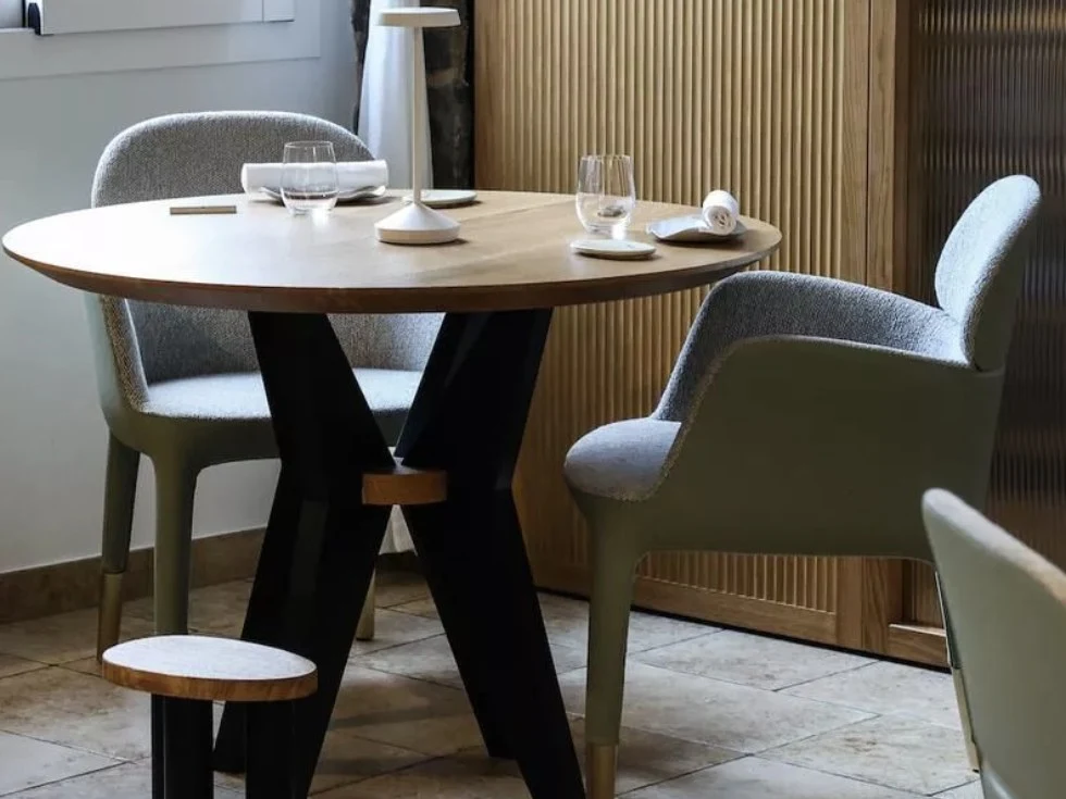 Dining table with two chairs and glassware in a modern interior.