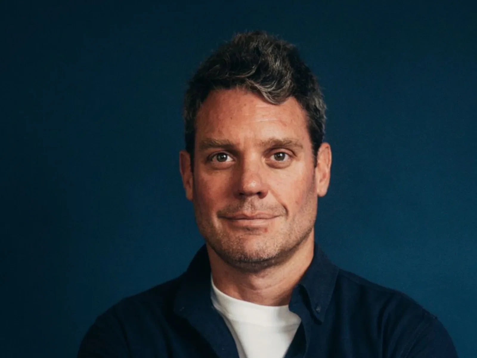 Portrait of a man against a dark blue background.