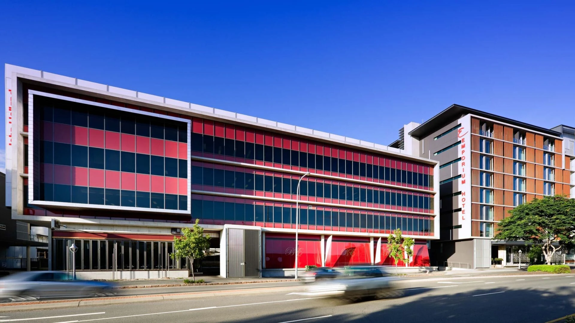 Modern commercial building exterior with distinctive red and dark blue checkerboard glass facade pattern; source page explicitly identifies this as Th