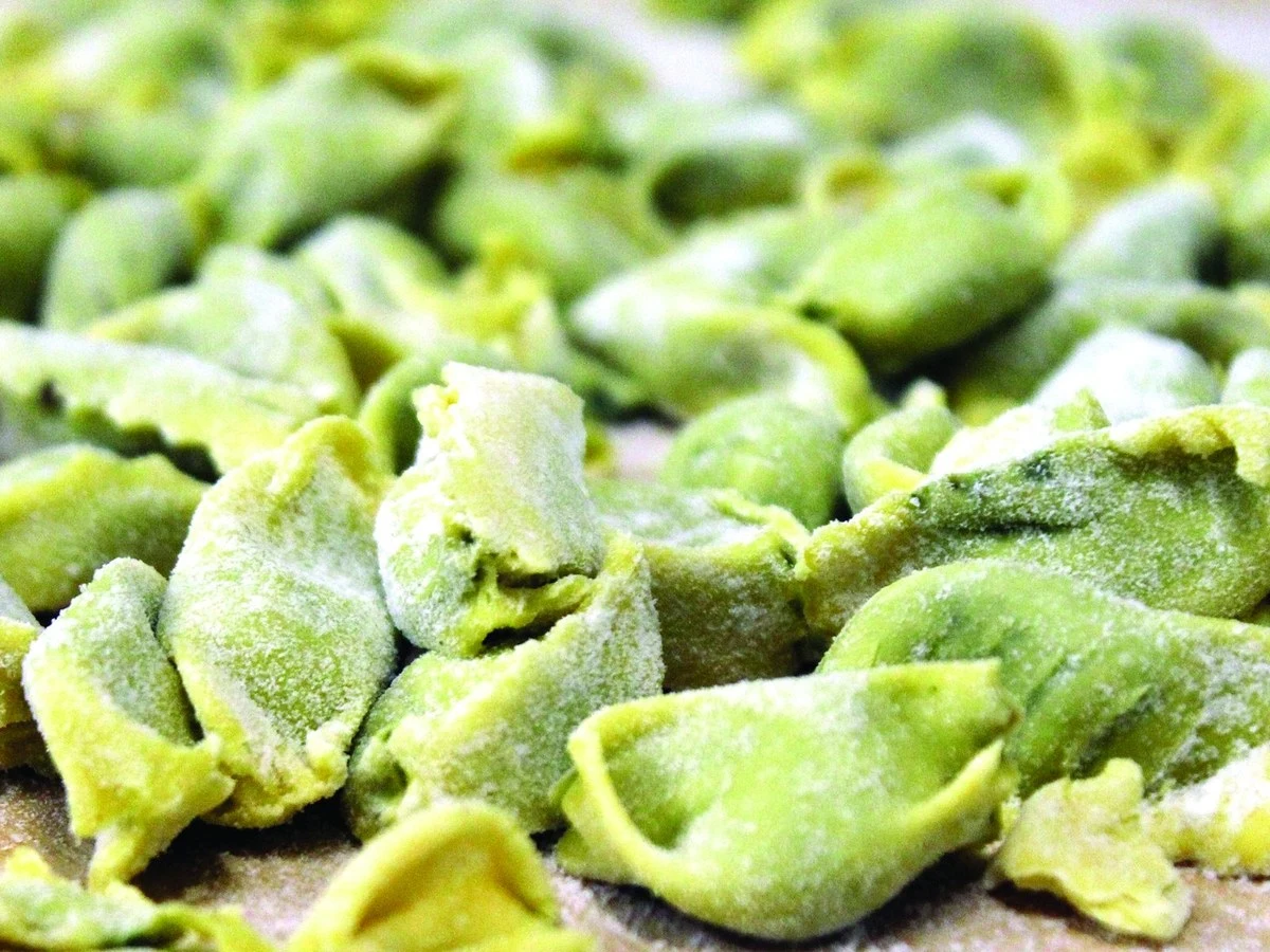 Green pasta pieces on a wooden surface.