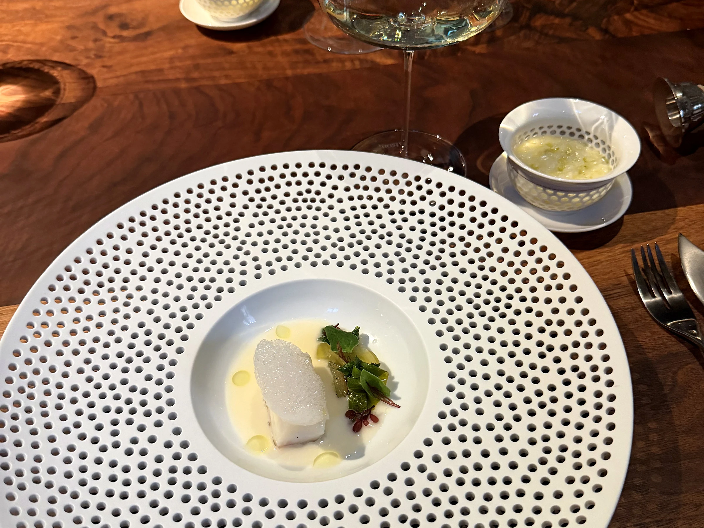 Saison seafood course served in a perforated white porcelain plate