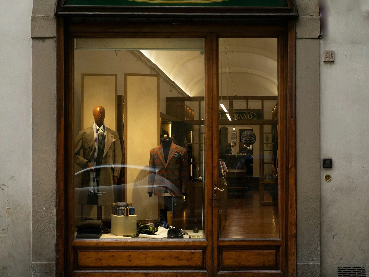 The arched entrance of Liverano & Liverano on Via dei Fossi, with its green oval sign and two mannequins in suits visible through the glass.