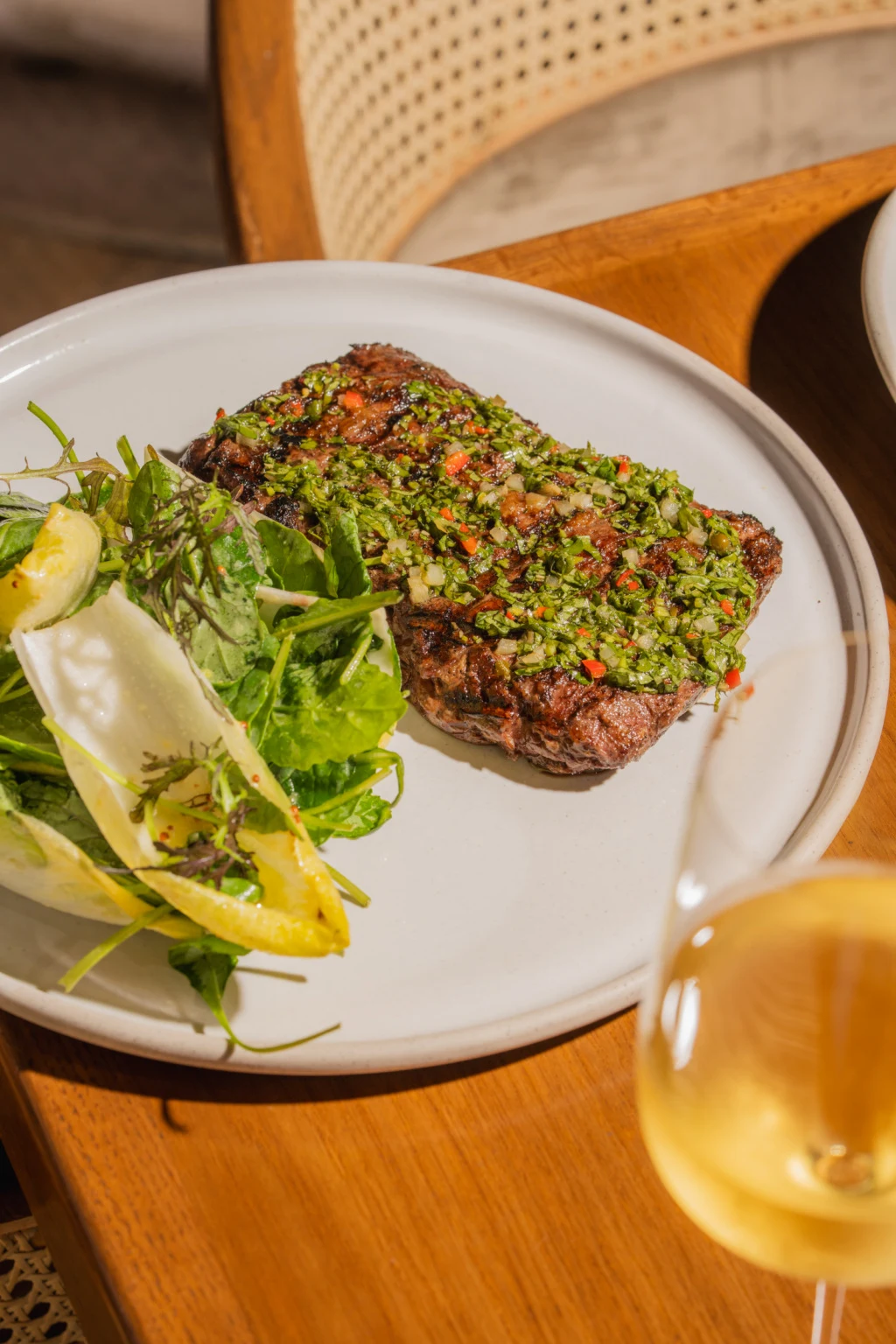 A plated filet mignon with herb topping and side salad.