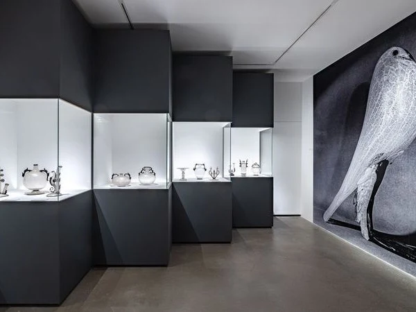 La Stanza del Vetro on San Giorgio Maggiore: Illuminated Murano glass objects against dark walls and a glass bird mural.