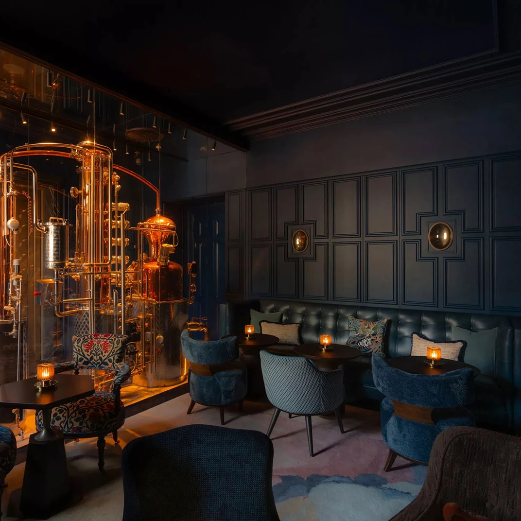 Advocatuur's luxurious interior features a prominent copper distillation apparatus and dark paneled walls.