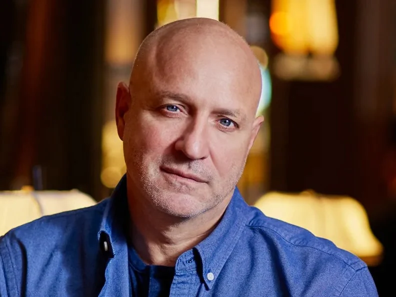 Tom Colicchio, chef-owner of Craft, in a warmly lit restaurant interior.