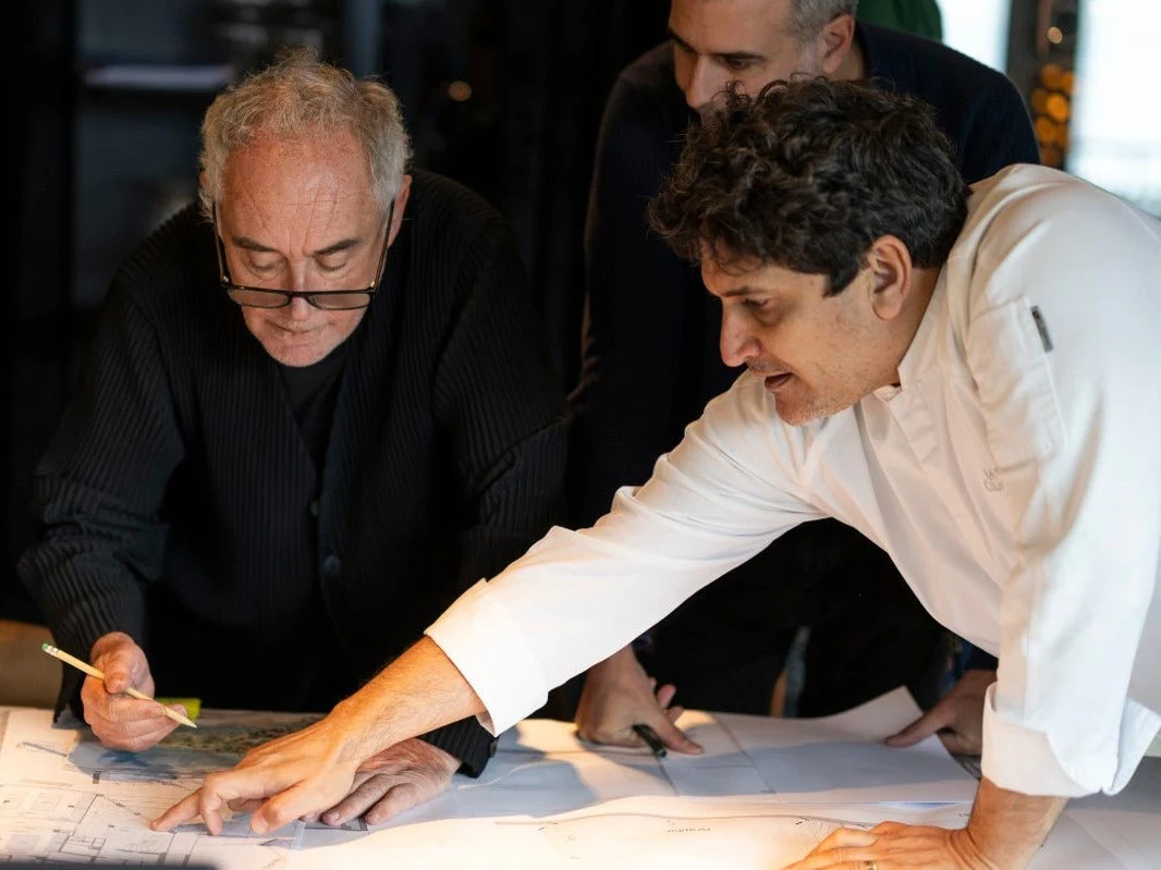 Three people examining architectural plans on a table.