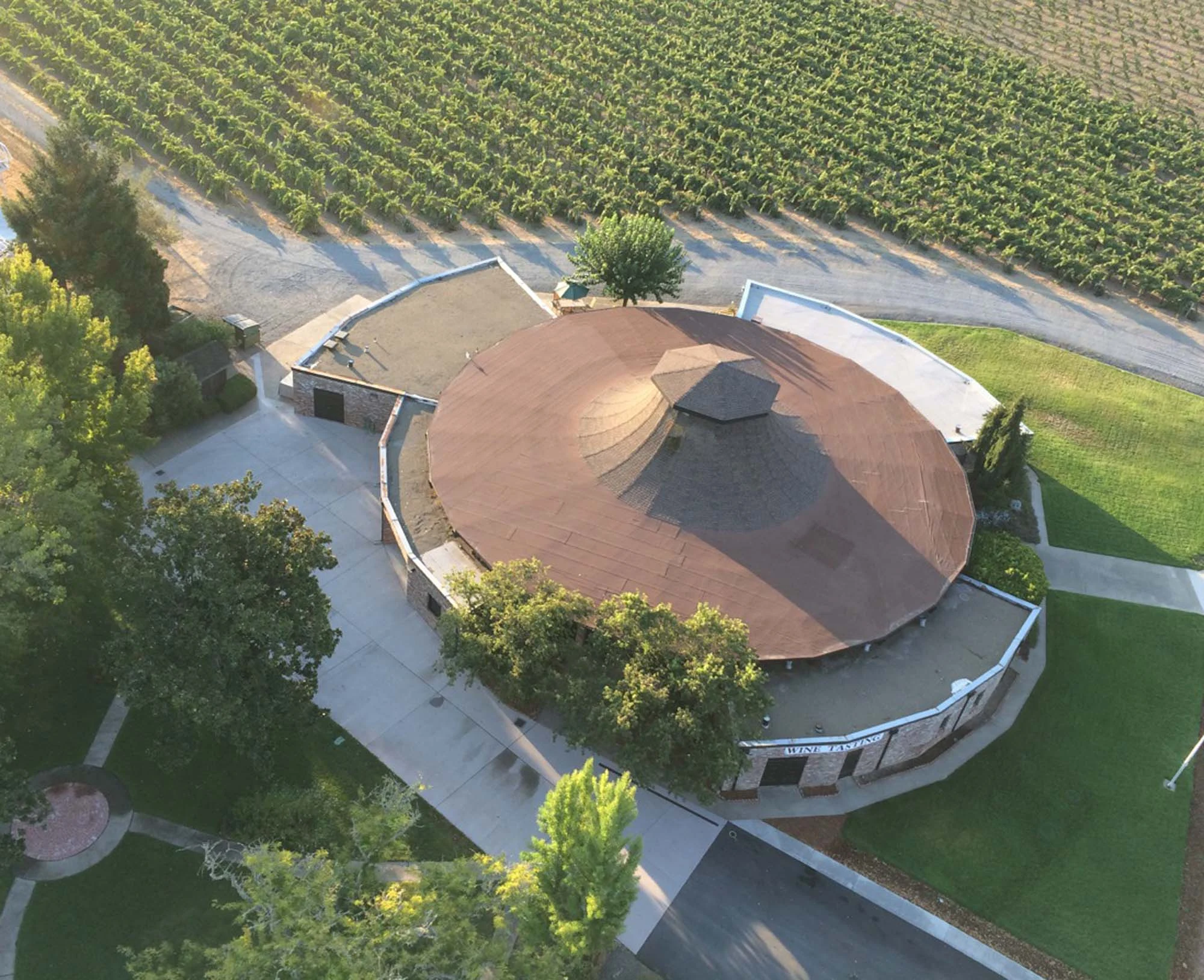 Aerial view of a circular winery building with distinctive brown dome roof surrounded by vineyards