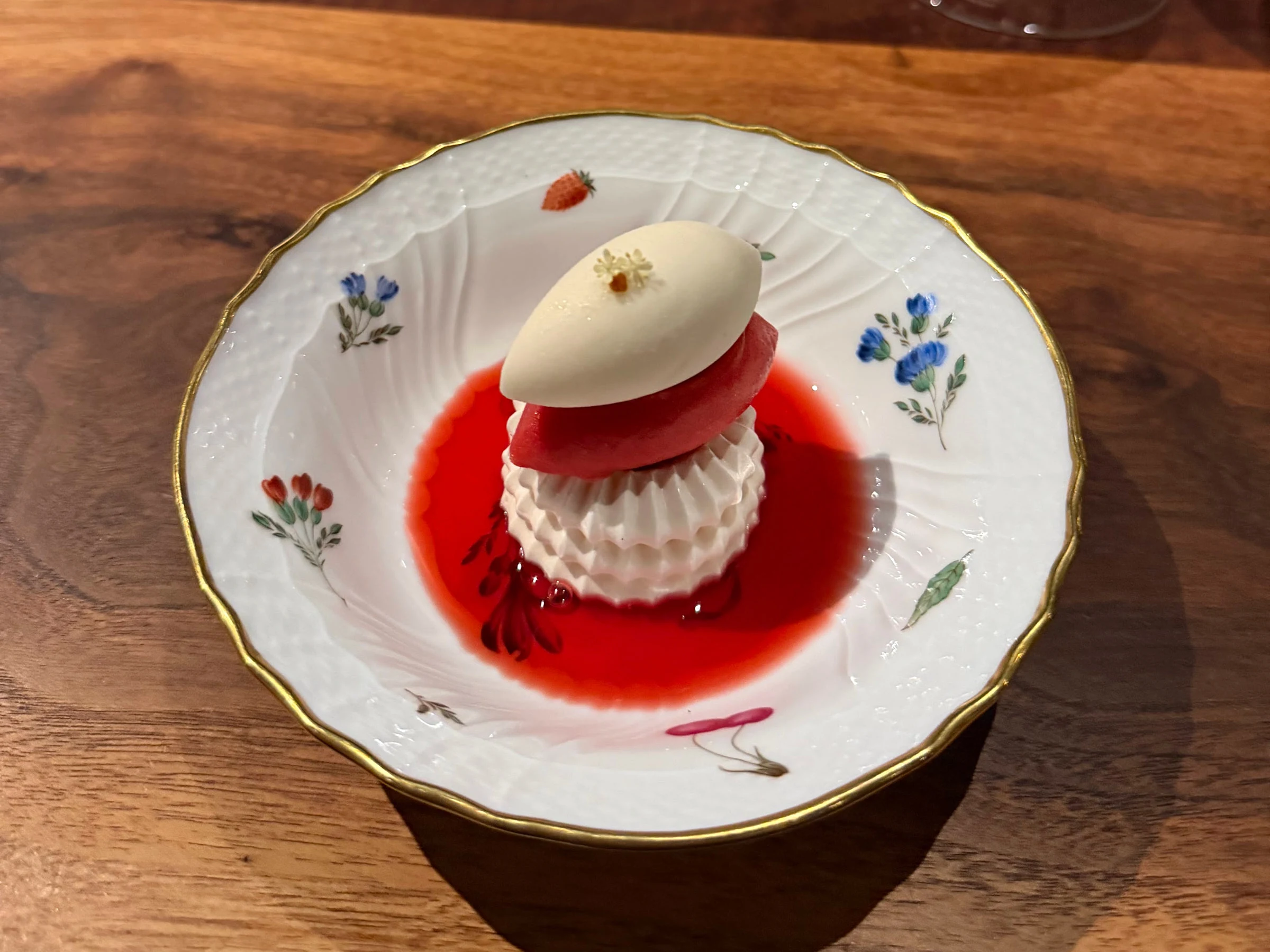 Red and white composed Saison dessert served on a gold-rimmed floral porcelain plate