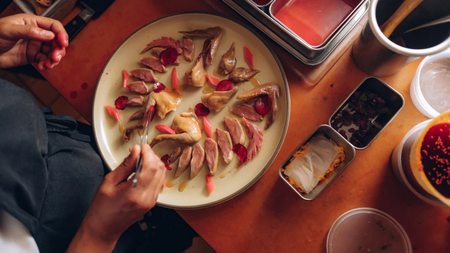 A dining scene at Mister Jiu's showing potstickers (a signature dish) being plated with rose petals, with the source page explicitly attesting this is