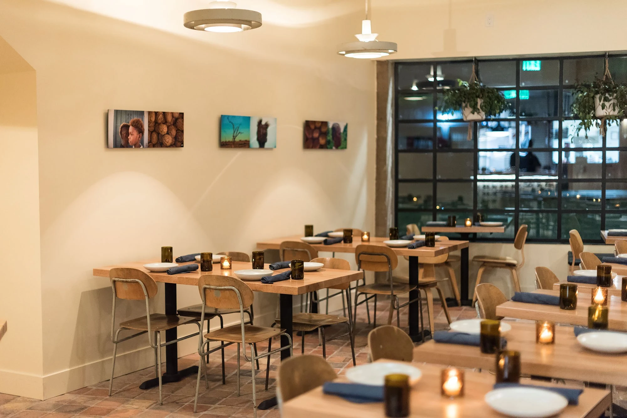 Alta Adams' modern dining room, featuring light wood tables, contemporary chairs, and artwork.
