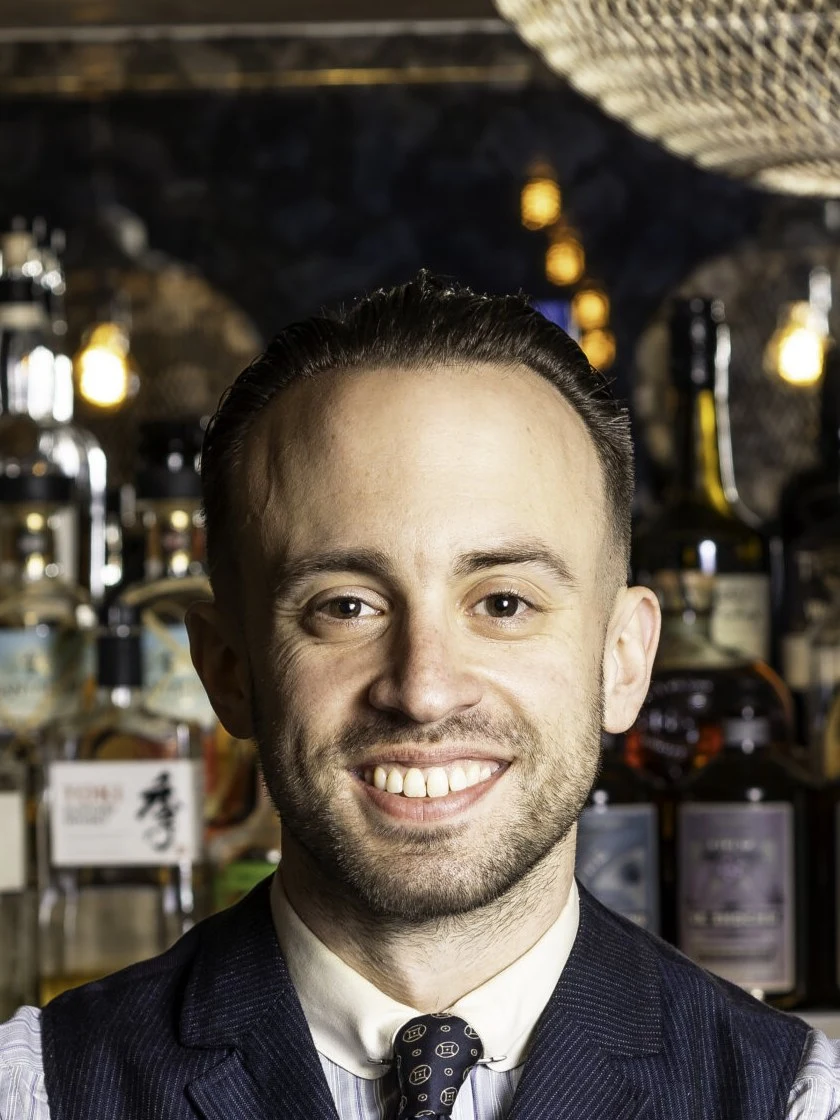 Ben Yabrow behind a well-stocked bar, ready to craft drinks.