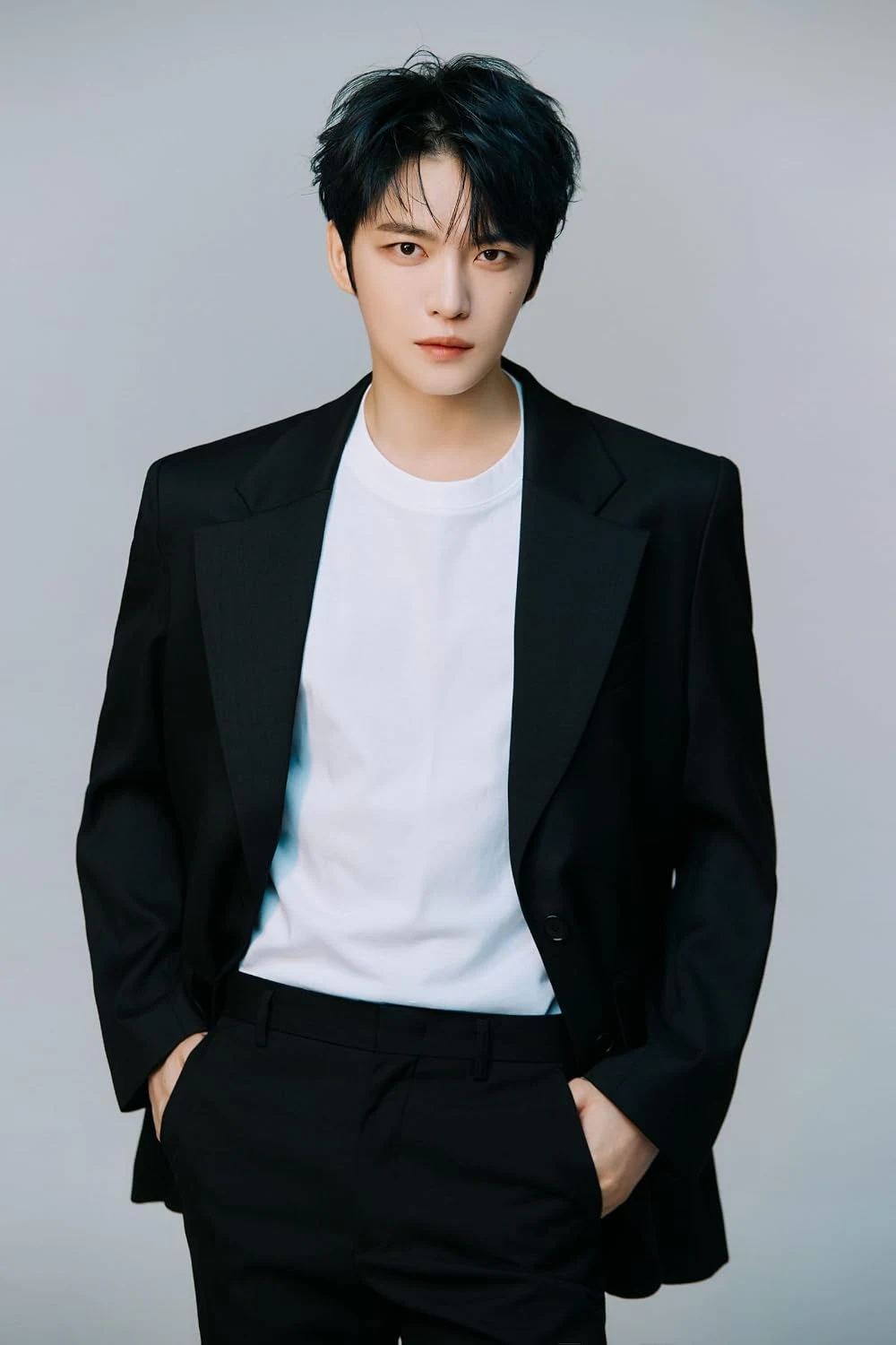 Professional studio portrait of a young person in a black blazer and white t-shirt against a neutral background; high-quality editorial photography bu