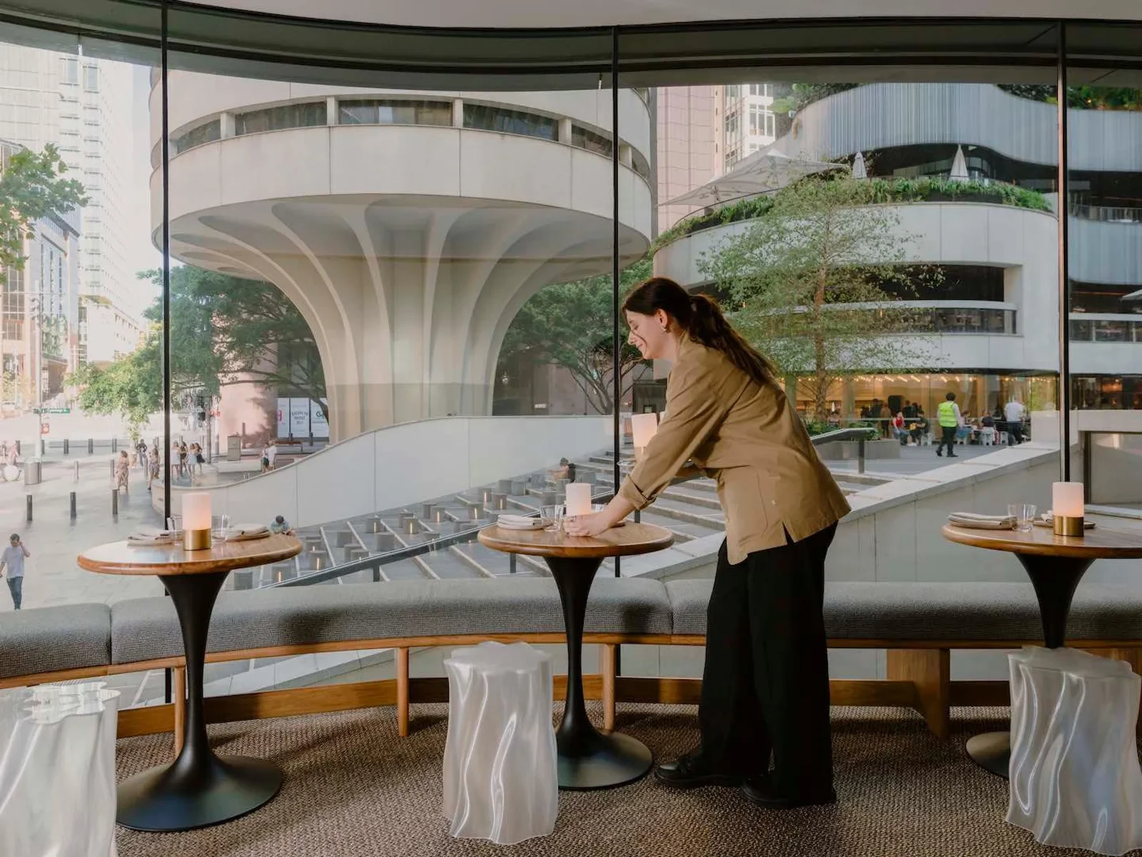 Aalia Wine Room interior with tables, glass walls, and urban landscape view.