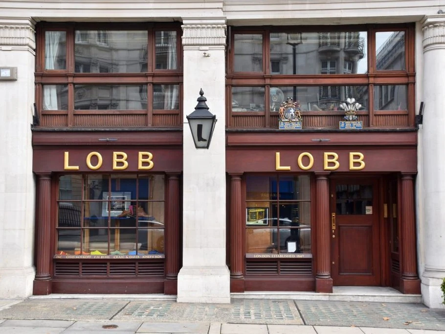 The exterior of John Lobb, a bespoke shoemaker, featuring two dark mahogany shopfronts with gold 'LOBB' lettering and large display windows.