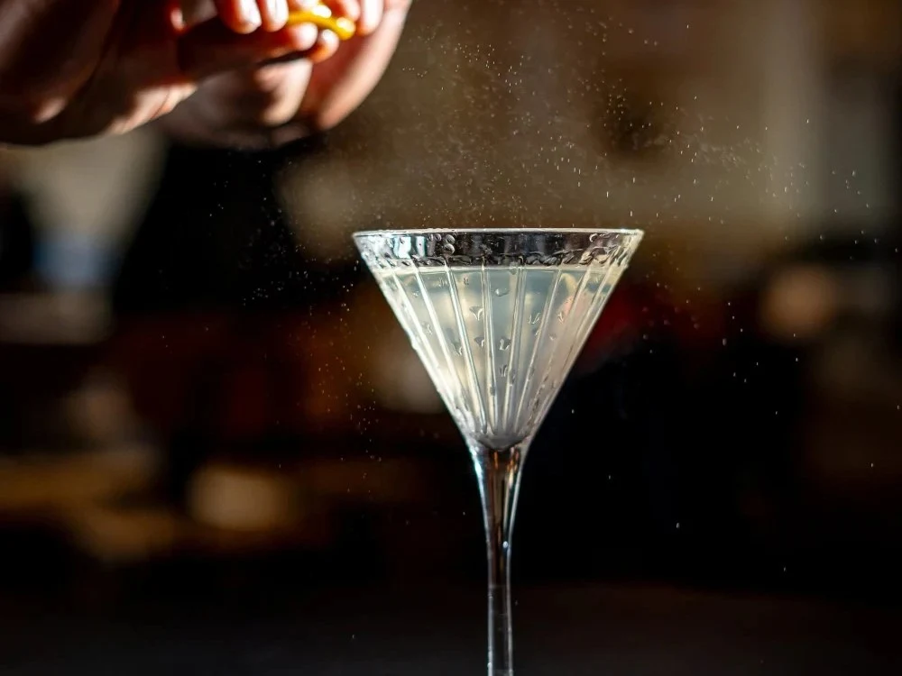 Limo Bar's Clean Dirty Martini, with a bartender squeezing citrus over the elegant glass.