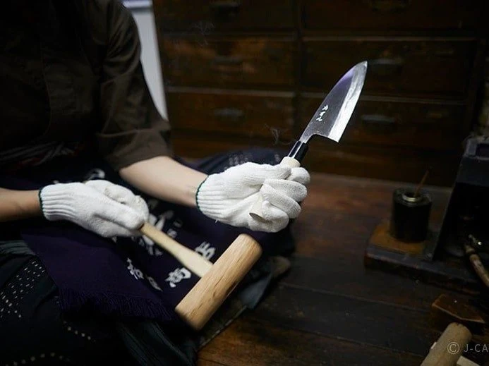 A craftsperson demonstrates the intricate art of knife forging, a hallmark of Sakai knife forges.