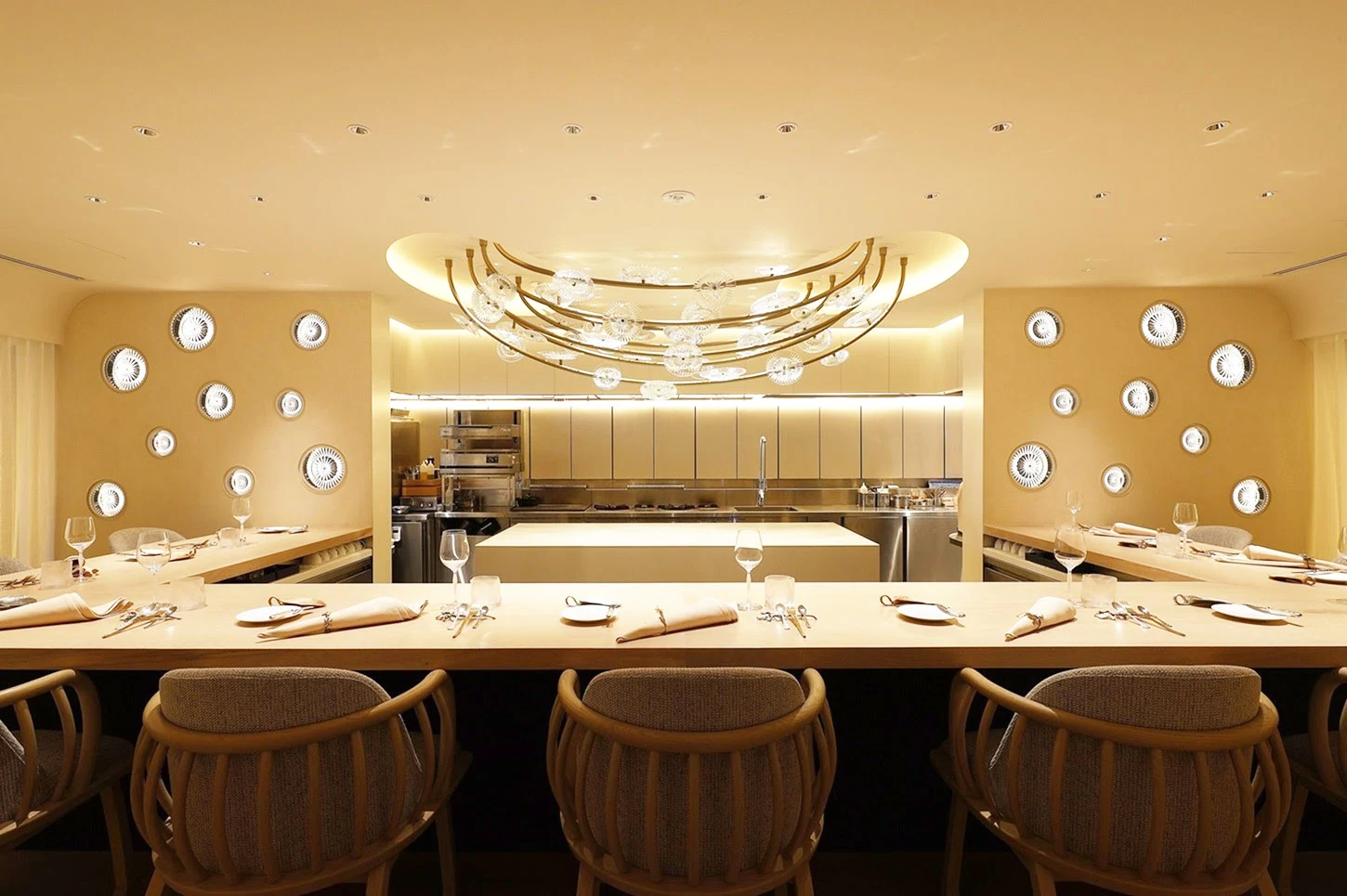 Sézanne's elegant counter dining and open kitchen, with unique wall decor and a curved crystal chandelier.