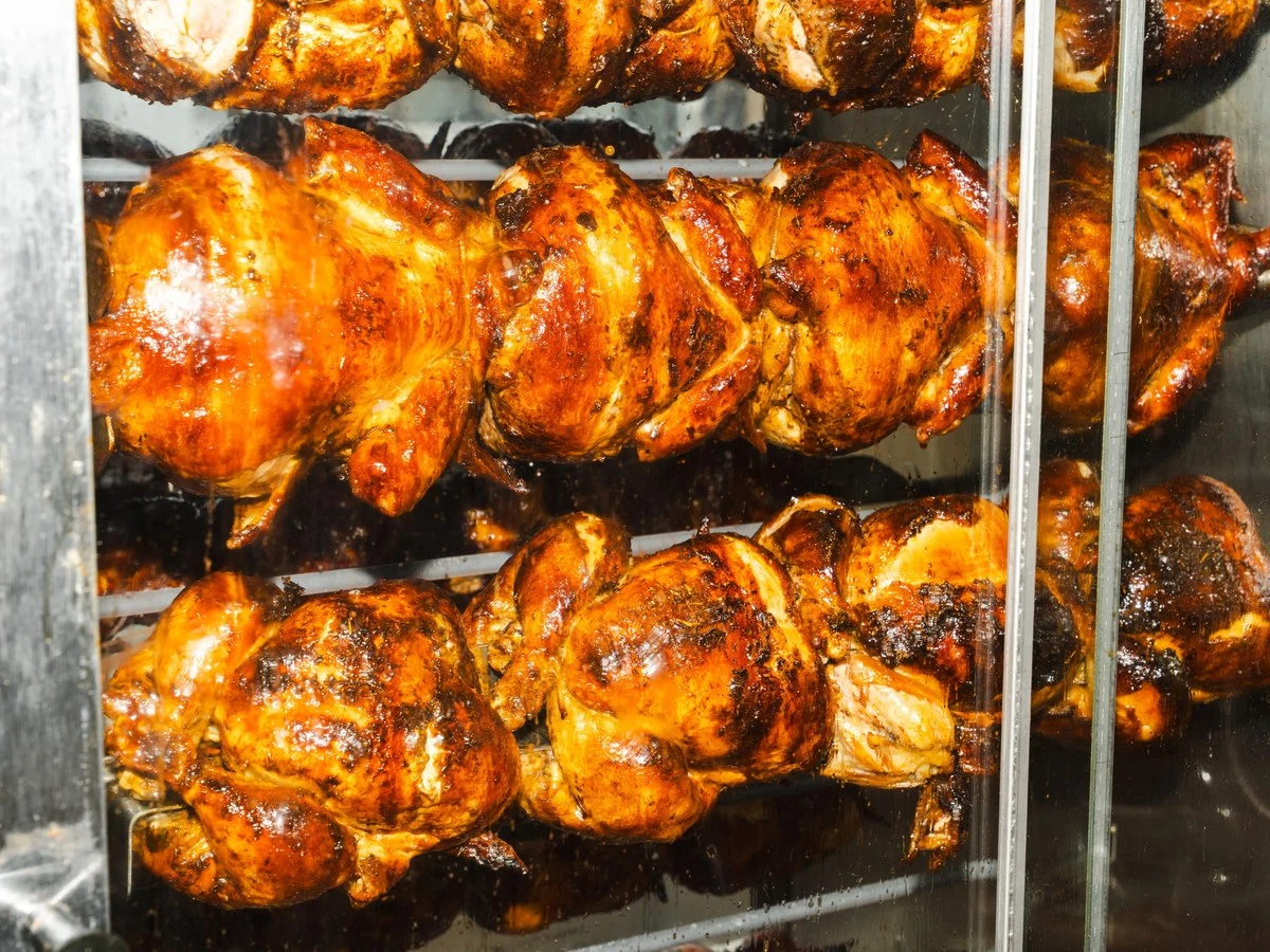 Rotisserie chickens on spits in a commercial rotisserie oven, beautifully glazed and caramelized