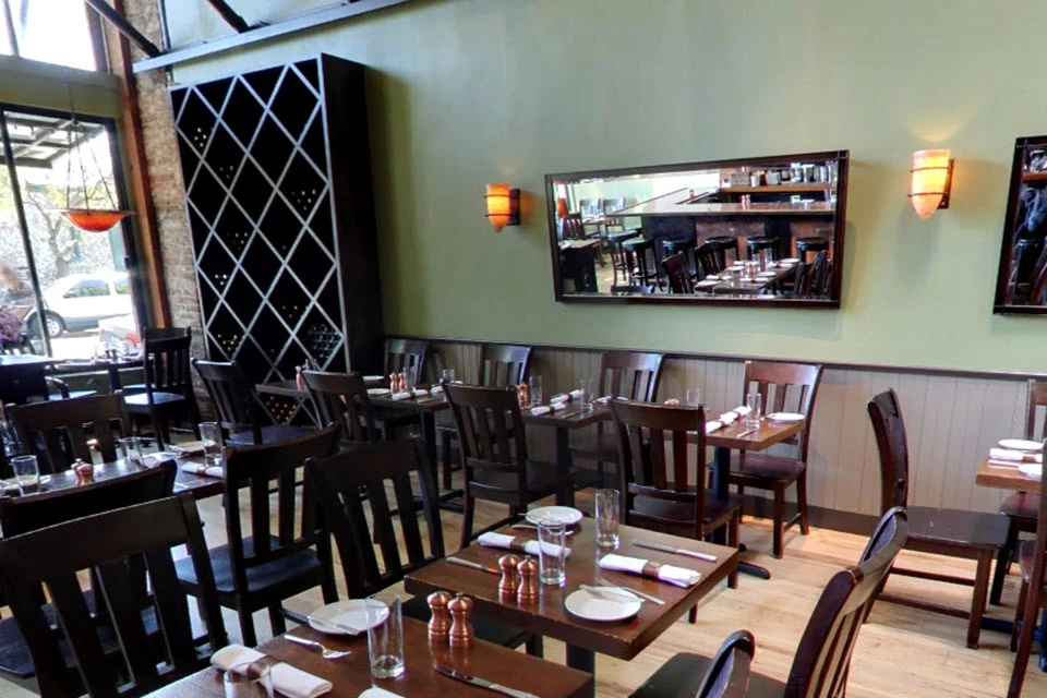 Wood Tavern's dining room, the space Uncle's will inherit, features dark wood furniture and sage green walls.