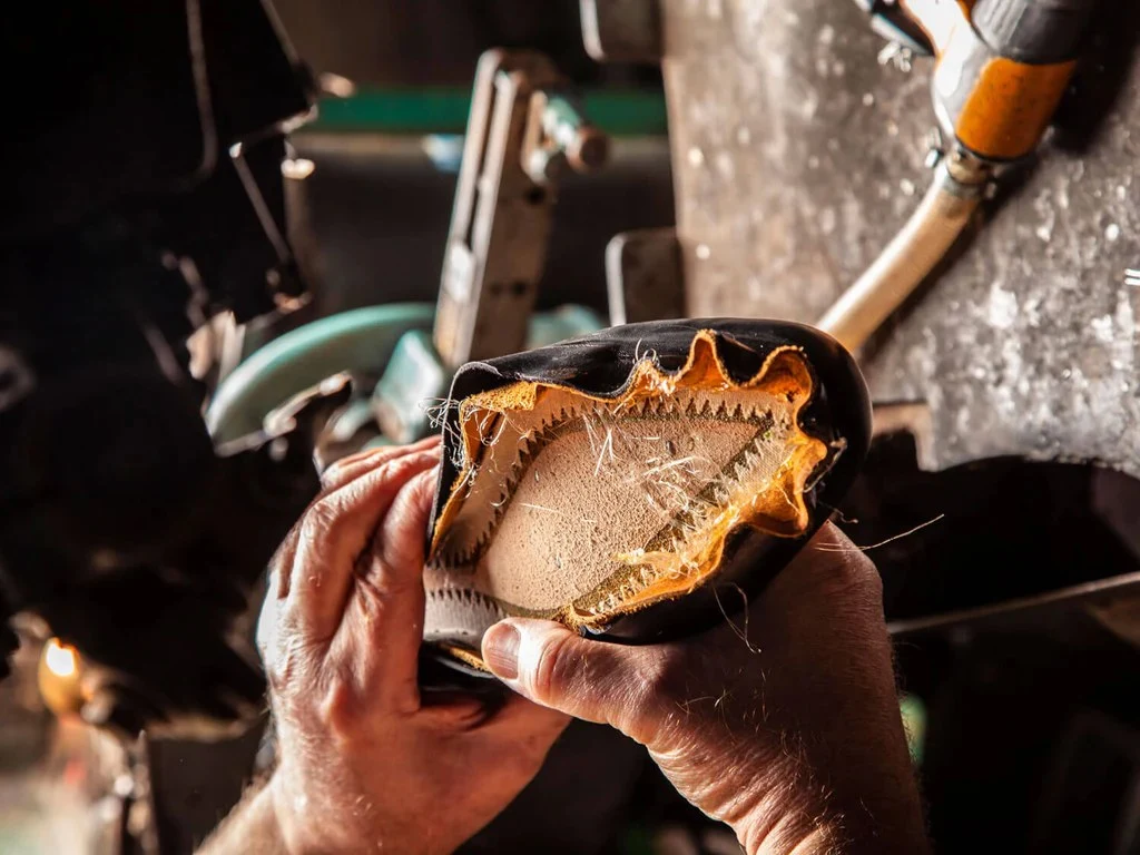 A Northampton workshop craftsman's hands reveal the intricate layers of a bespoke shoe in progress.