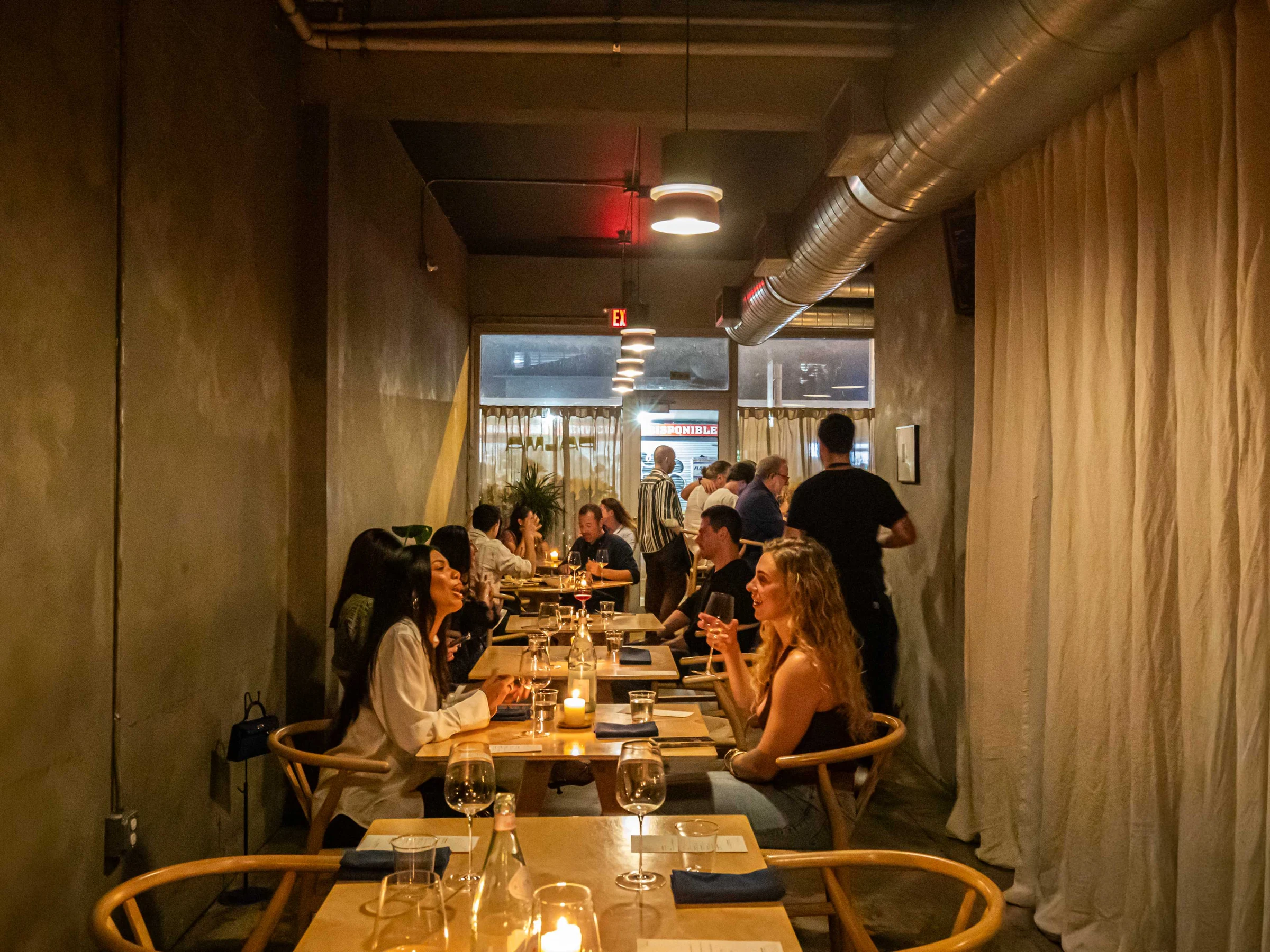 Las' Lap Miami's dim dining room features concrete walls, exposed ductwork, and pendant lighting.