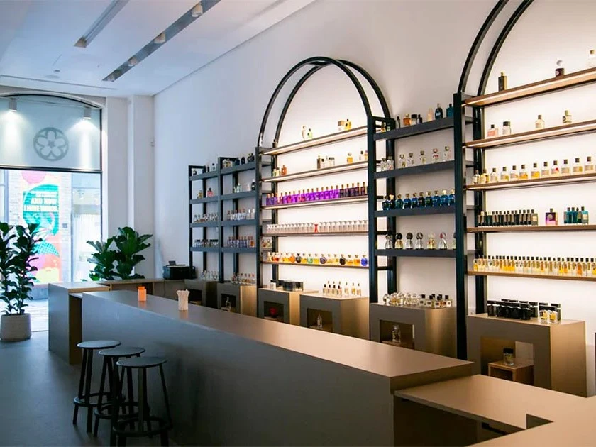 Interior of Bloom Perfumery in Covent Garden, London, featuring brightly lit shelves displaying hundreds of perfume bottles.
