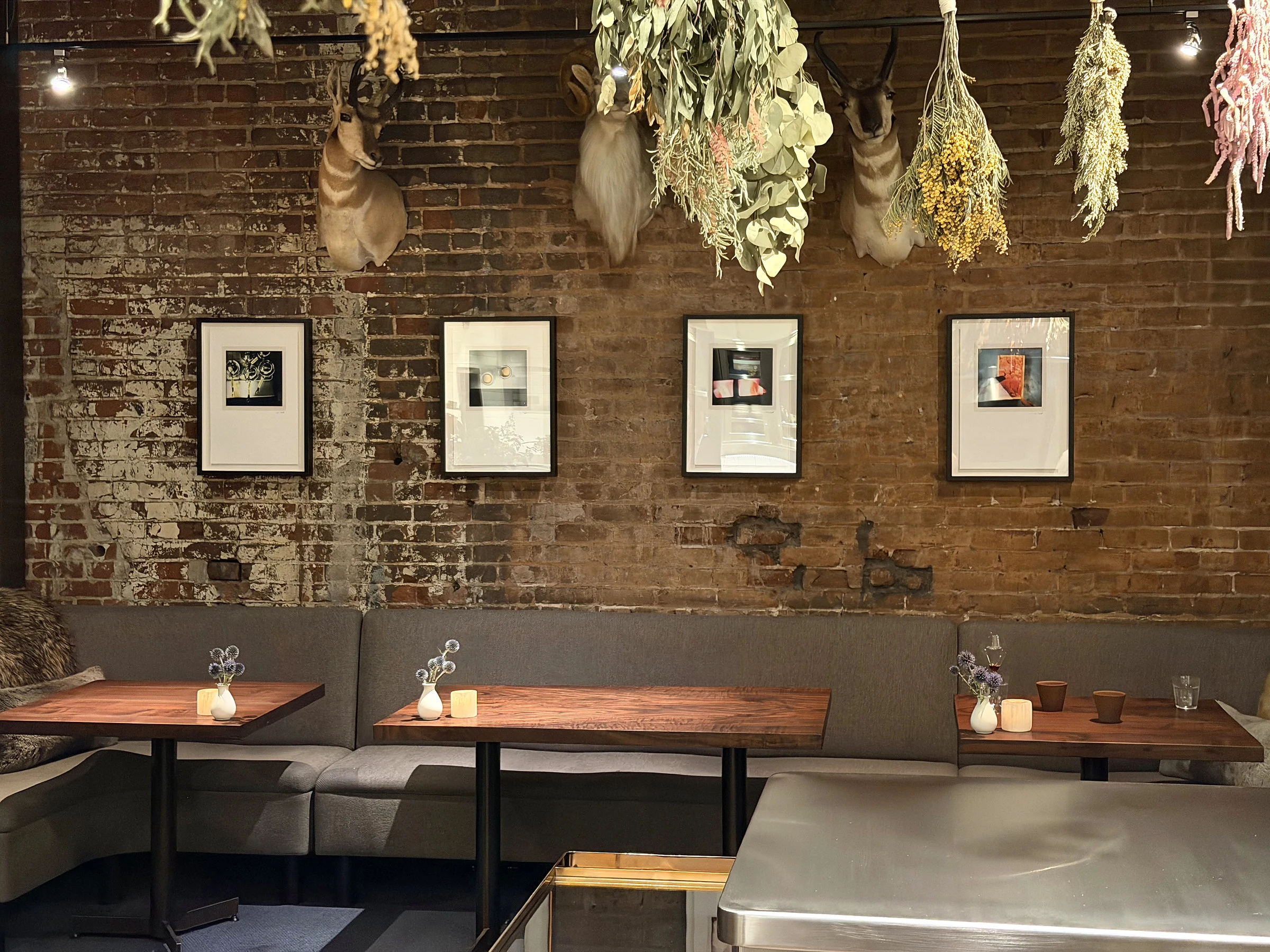 Saison dining room with brick walls, framed art, dried botanicals, and banquette seating